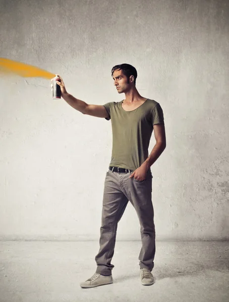 Jonge man met een oranje spray — Stockfoto