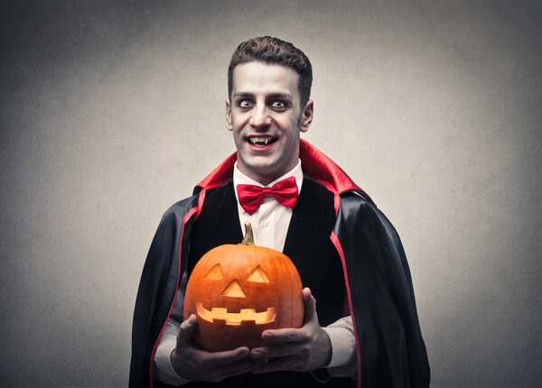 Vampire holding a Halloween pumpkin