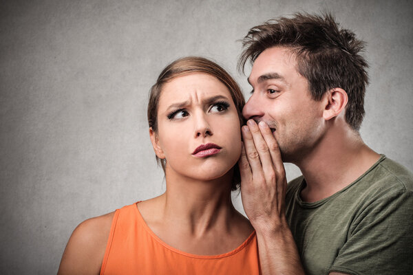 Man telling a secret to a woman