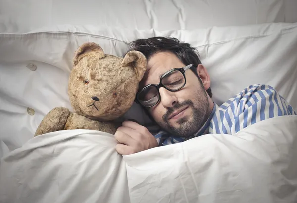 Mann hält seinen Teddy ins Bett — Stockfoto