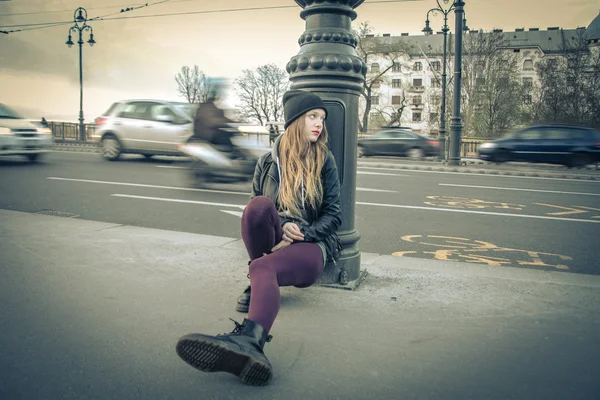 Jeune femme assise sur la chaussée — Photo