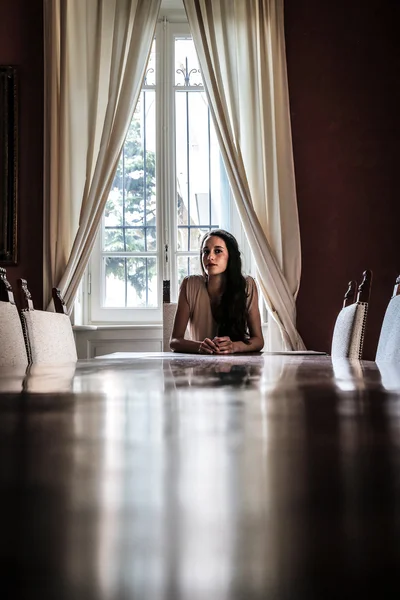 Mujer joven sentada a la mesa —  Fotos de Stock