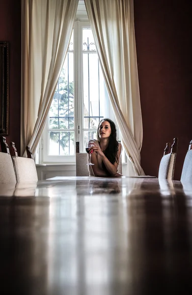 Jovem mulher sentada à mesa — Fotografia de Stock