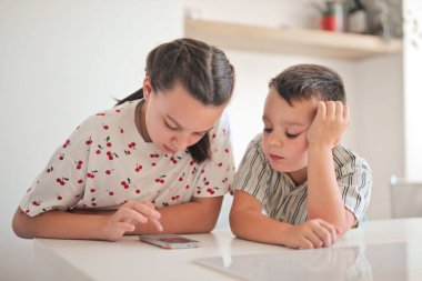 İki çocuk mutfakta akıllı telefon kullanıyor.