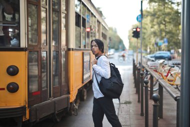 Genç adam şehirde tramvaya biniyor.