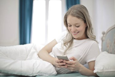 Leto giymiş genç bir kadın akıllı telefon kullanıyor.