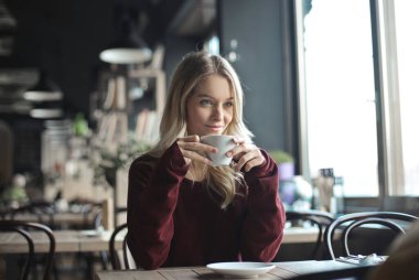 Kafede kahve içen genç bir kadın.