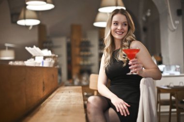 Genç bayan bir barda kokteyl içiyor.