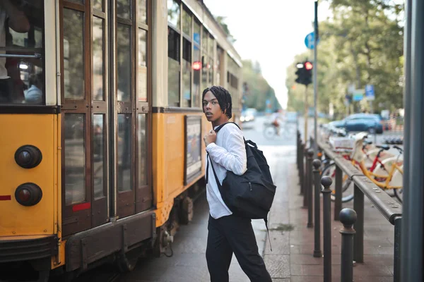 Genç adam şehirde tramvaya biniyor.