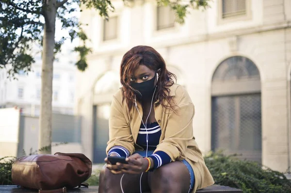 Mujer Joven Con Máscara Sentada Banco Escucha Música —  Fotos de Stock