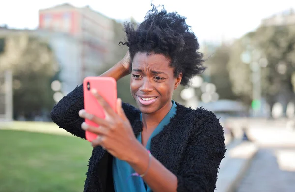 Jovem Mulher Olha Para Seu Smartphone Decepcionado — Fotografia de Stock