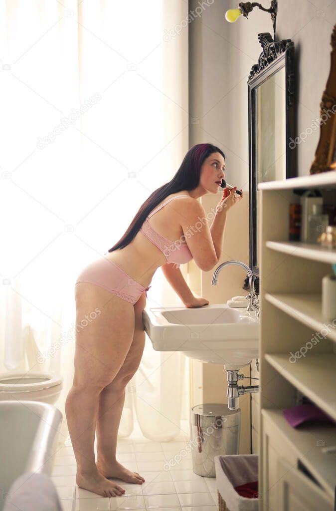 young woman puts on makeup in the bathroom