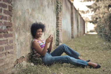 Genç bir kadın parkta akıllı telefon kullanıyor.