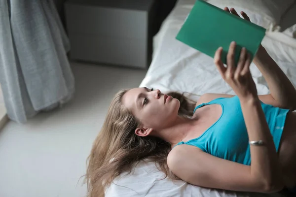 Μια Γυναίκα Διαβάζει Ένα Βιβλίο Ξαπλωμένο Ένα Κρεβάτι — Φωτογραφία Αρχείου