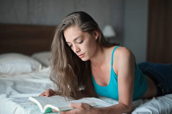 Μια Νεαρή Γυναίκα Διαβάζει Ένα Βιβλίο Ένα Κρεβάτι — Φωτογραφία Αρχείου