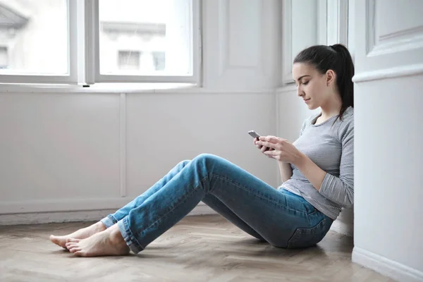 Young Woman Sitting Floor Writes Smartphone — стоковое фото