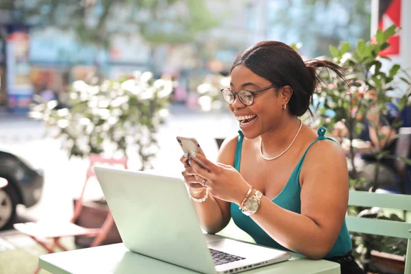 若い女性は屋外のカフェでコンピュータとスマートフォンを使い — ストック写真
