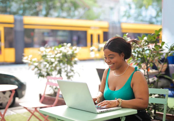 外のカフェの若い女性はコンピューターを使って — ストック写真