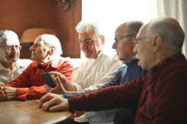Bir grup son sınıf öğrencisi evde akıllı telefon kullanıyor.