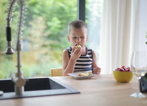 子供は台所で果物を食べる — ストック写真