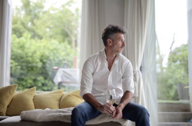 Adam evde şarap içiyor.