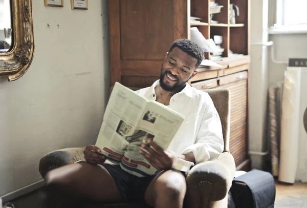 Retrato Del Joven Sonriendo Mientras Lee Periódico Sentado Sillón — Foto de Stock