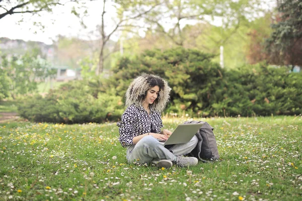 若い女性は公園でコンピューターを使い — ストック写真