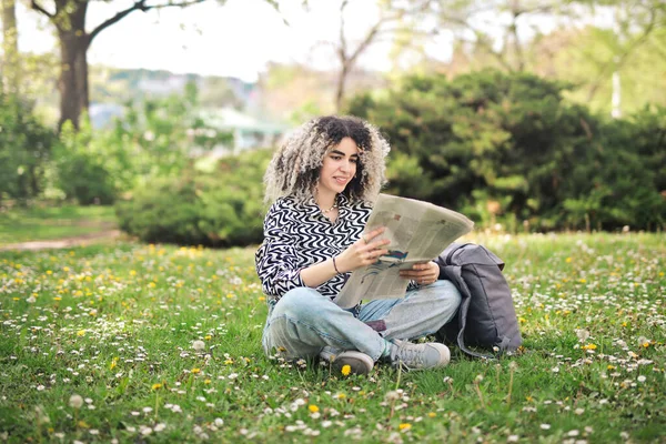 公園で新聞を手にした若い女性が — ストック写真