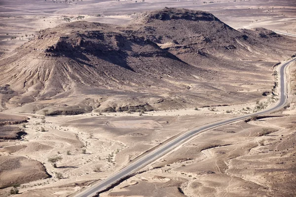 Paesaggi desertici pietrosi con strada asfaltata nel Sahara . — Foto Stock