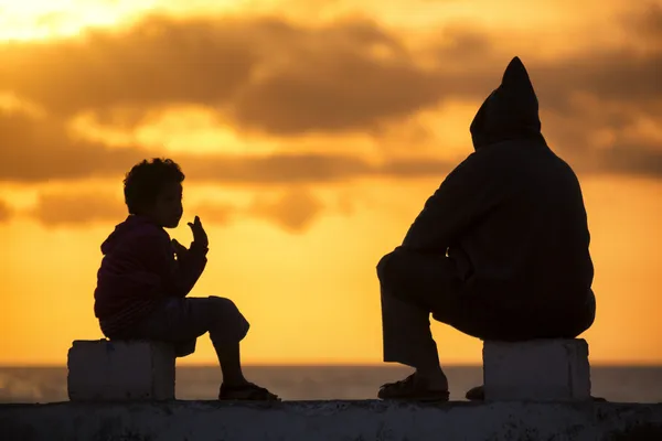 A boy and a man watching the sunset in Essaouira. — Stock Photo, Image