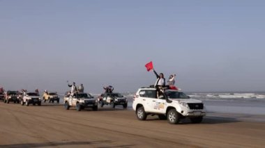 Essaouira, Marakeş, Fas - 2 Ekim 2021: Rallye Aicha des Gazelles 2021. Sunum seremonisi için rallye 2021 'in sonunda Essaouira sahiline arabaların varışı. Fas bayrağı.