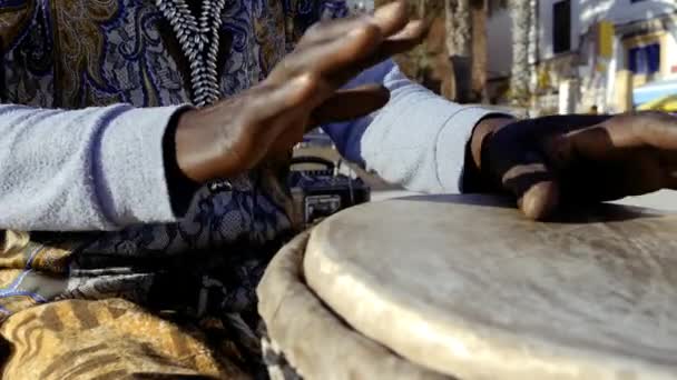 セネガル人の男性は手で伝統的なジェムドラムを演奏する 西アフリカの伝統音楽は通りや祭りで演奏されることが多い — ストック動画