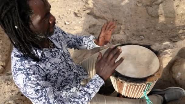 アフリカの打楽器音楽で セネガル人の男性が手で伝統的なジェムドラムを演奏します 西アフリカの伝統音楽は通りや祭りで演奏されることが多い — ストック動画