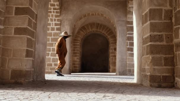 Tradičně Oblečený Marocký Muž Kapucí Slaměným Kloboukem Prochází Klenutým Vchodem — Stock video