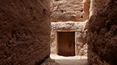 Beyaz gandoura giyen geleneksel giyinmiş Faslı bir adam ve Tamnougalt, Fas 'ta bir Kasbah' ın içinde türban yürüyor. Güney Fas 'ın otantik kırsal manzarası. 4k.