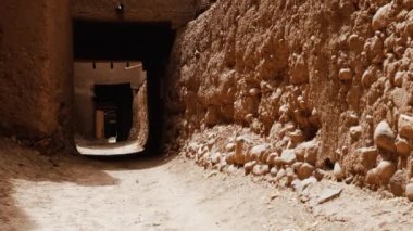 Beyaz gandoura giyen geleneksel giyinmiş Faslı bir bedevi ve Tamnougalt, Fas 'ta bir Kasbah' ın içinde türban yürüyor. Güney Fas 'ın otantik kırsal manzarası. 4k.