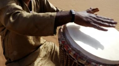 Faslı bir adam çölde geleneksel bir djembe davul çalar. Geleneksel Afrika müziği genellikle çölde ve festivallerde çalınır. 4k