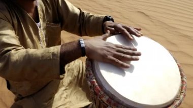 A Moroccan man plays a traditional djembe drum in the desert. Nord-African traditional music is often played in the desert and on festivals. 4k