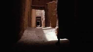 Beyaz gandoura giyen geleneksel giyimli Faslı bir Bedevi adam Tamnougalt, Fas 'ta bir Kasbah' ın içinde yürüyor. Güney Fas 'ın otantik kırsal manzarası. 4k. 
