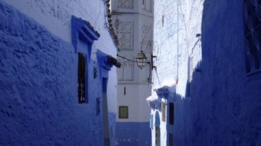 Street detail with blue painted houses and a mosque in the Medina of Chefchaouen, Morocco. Famous touristic travel destination. 4k footage.