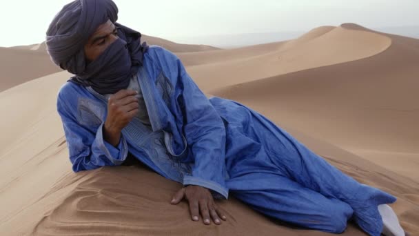 Moroccan Man Wearing Blue Gandoura Djellaba Turban Rests Top Sand — Stock video