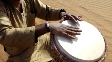 A Moroccan man plays a traditional djembe drum in the desert. Nord-African traditional music is often played in the desert and on festivals. 4k