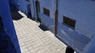 Chefchaouen, Tetouan, Fas - 28 Temmuz 2022: Fas 'ın başkenti Chefchaouen' de geleneksel giyinmiş bir kadınla sokak sahnesi. Ünlü, popüler turist gezisi merkezi. 4k görüntü.