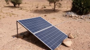 Sahra Çölü 'ndeki güneş enerjisi paneli, Erg Chigaga, Fas. Çöldeki hayvanlar ve ağaçlar için bir kuyudan su almak için güneş enerjisi. 4k görüntü.