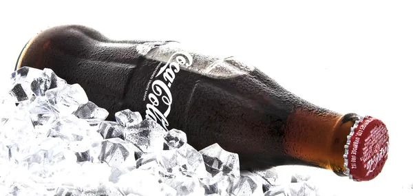 Bouteille classique de Coca-Cola sur un lit de glace sur un fond blanc — Photo