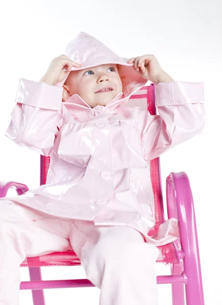 Little girl wearing raincoat sitting on chair — Stock Photo, Image