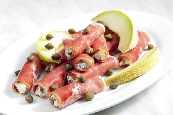 Parma ham rolls filled with cream cheese, Galia melon and capers