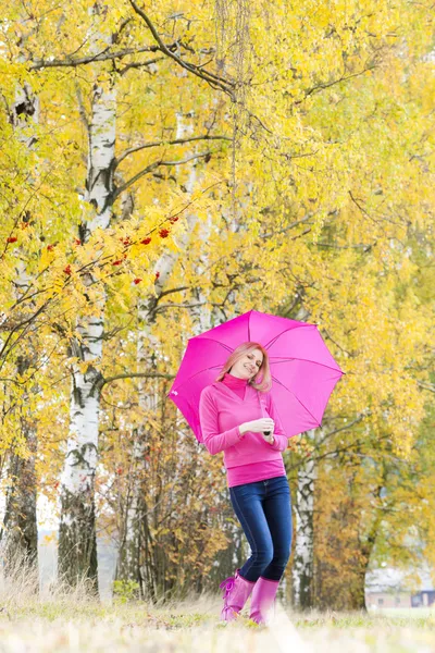 Kvinna som bär gummi stövlar med paraply i höstliga naturen — Stockfoto