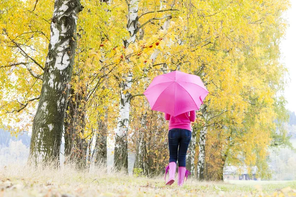 Frau trägt Gummistiefel mit Regenschirm in herbstlicher Natur — Stockfoto