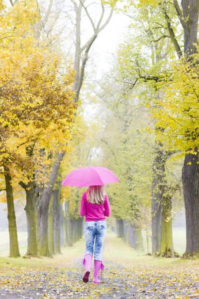 Mother and her daughter with umbrellas in autumnal alley — Stock Photo, Image